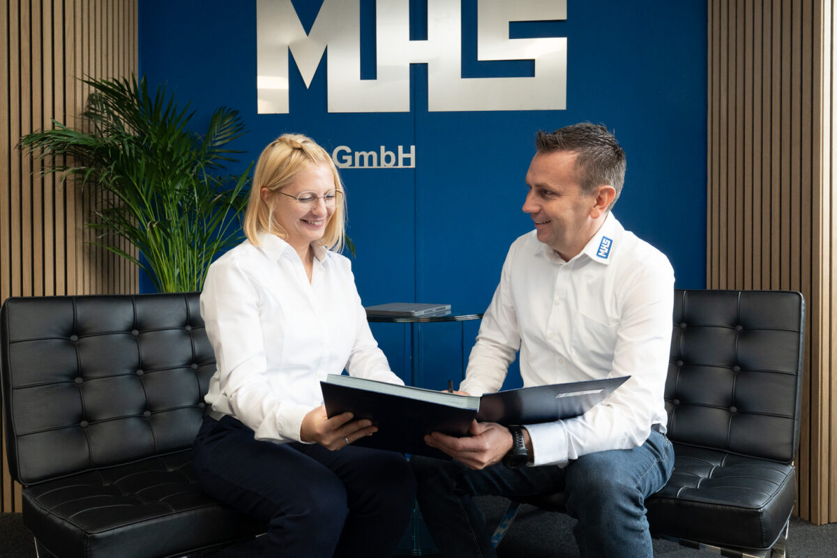 Melanie Schießl und Mathias Schießl bei einer Besprechung im Empfangsbereich der MHS GmbH. Gemeinsame Durchsicht von Unterlagen in entspannter Atmosphäre.